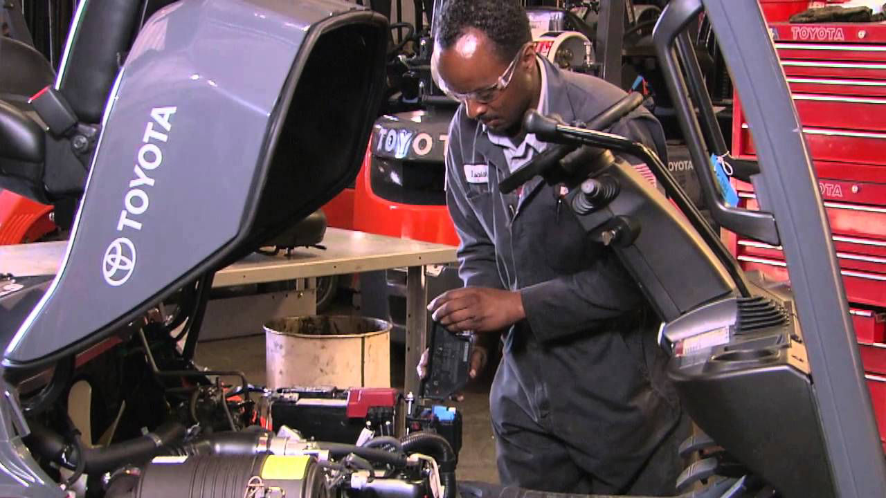 Técnico masculino trabajando en el motor de la carretilla elevadora en el almacén.