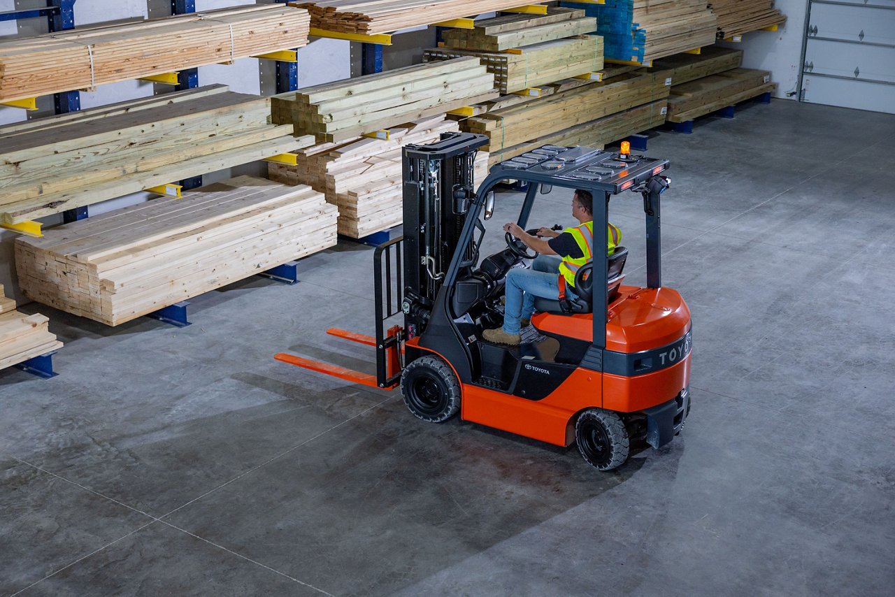 Orange 48V 80V driving in an indoor warehouse to pick up lumber to take to outside to lumberyard