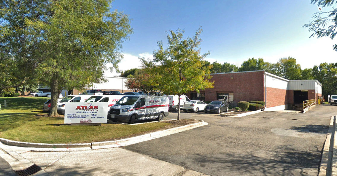 An orange brick building with white and red service trucks parked out front 