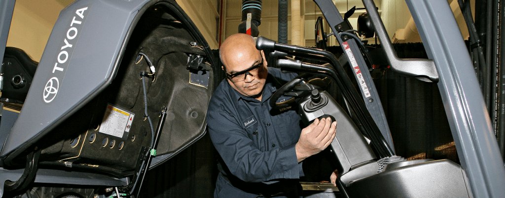 Primer plano de un técnico de montacargas masculino inspeccionando el interior de una carretilla elevadora. 