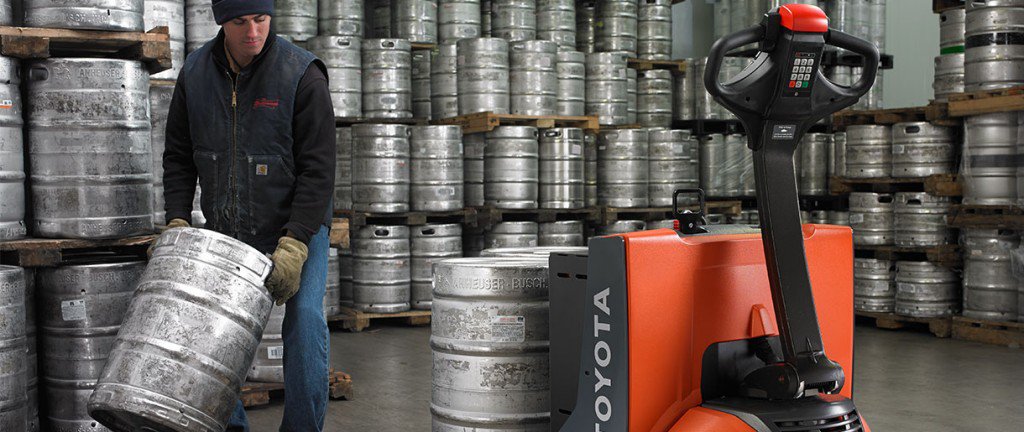 Man charging an electric walkie with 3 aluminum barrels in a cold store.