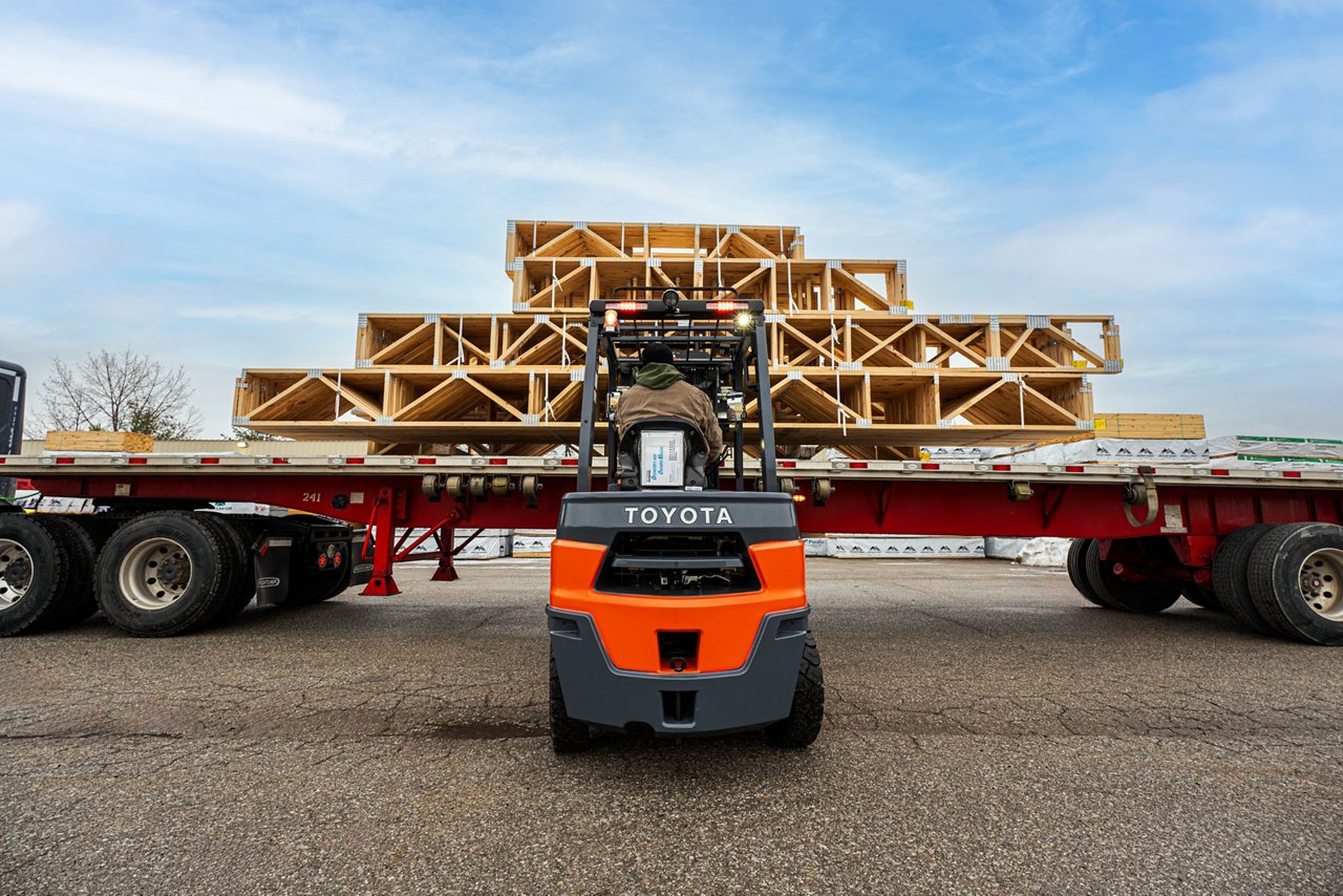 toyota diesel forklift unloading wood panels from a semi truck