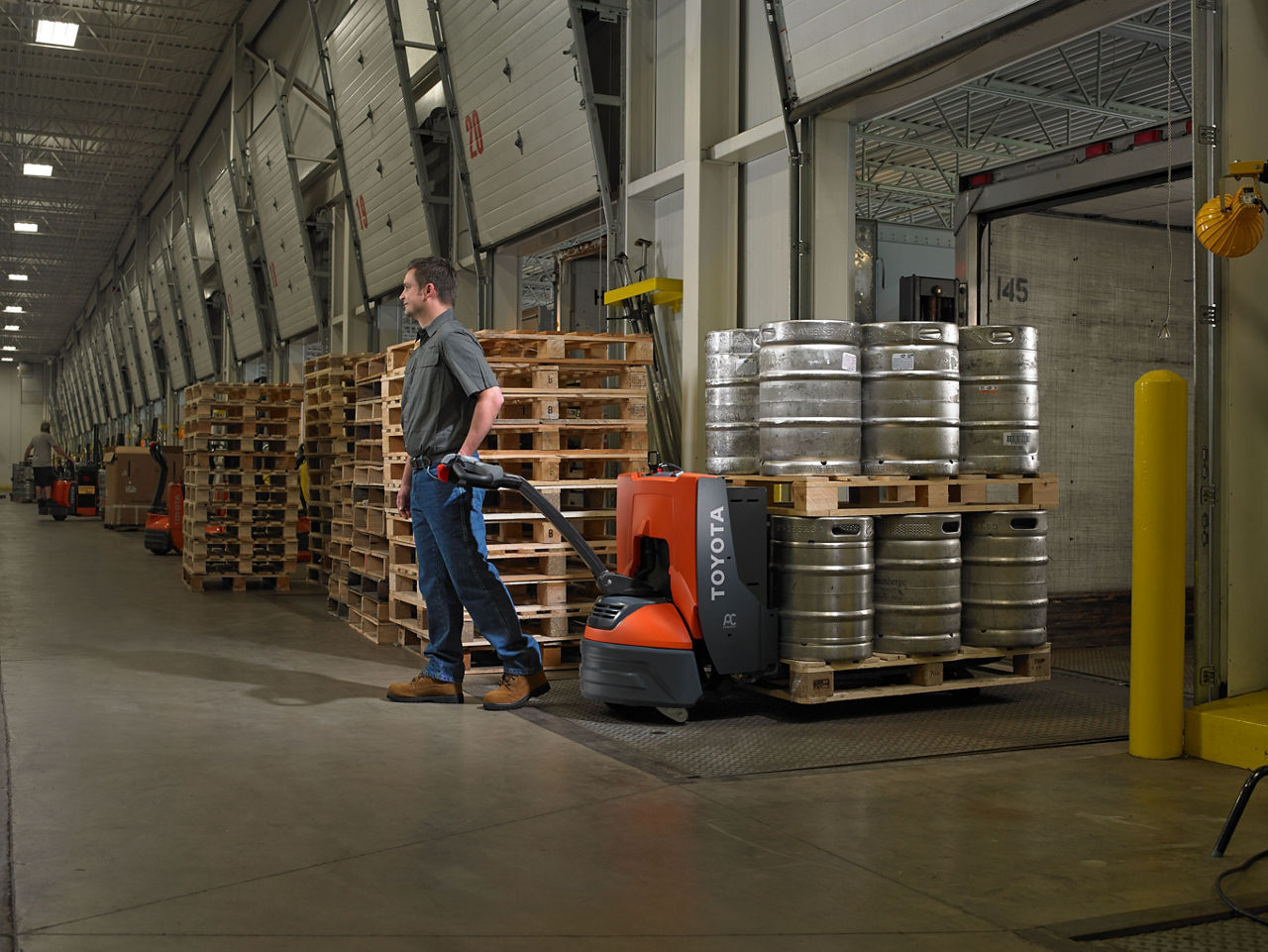 large electric pallet jack being used in warehouse carrying beer kegs