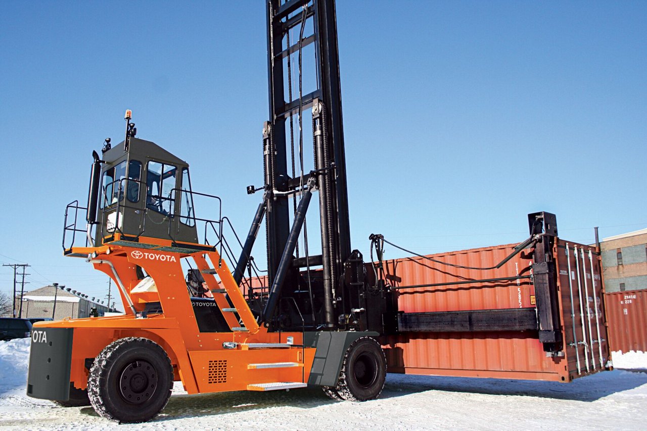 A Toyota empty container handler carrying a container in a loading lot outdoors.