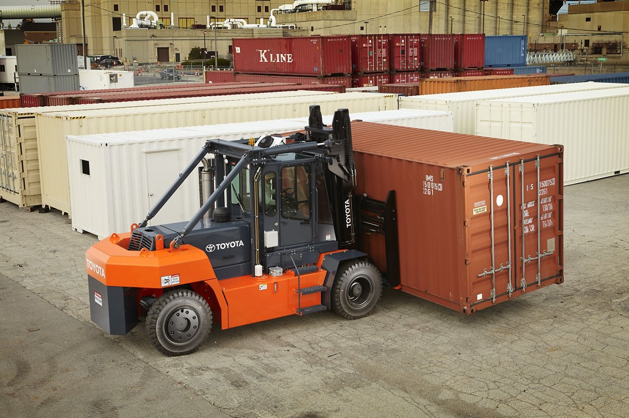 A forklift that moves while transporting a large container on a loading dock