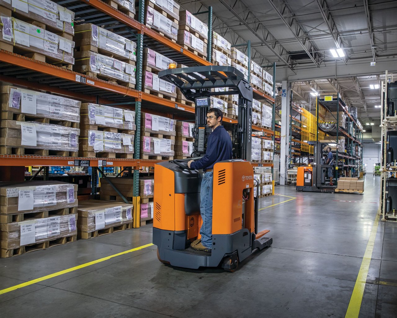 A man driving a Toyota forklift in a warehouse 