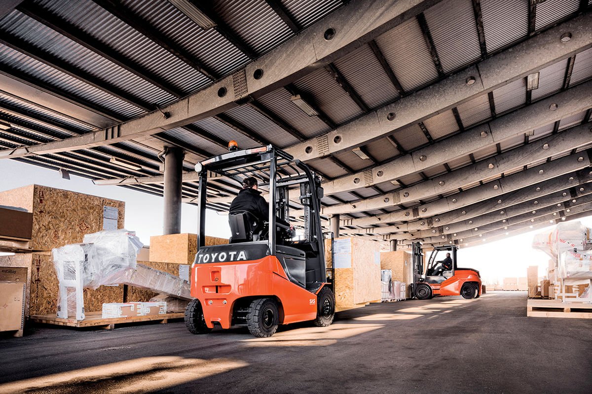 Carretilla elevadora neumática eléctrica grande Toyota en almacén al aire libre que transporta muchas cajas