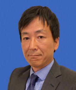 Portrait professionnel d’un homme japonais portant une veste de costume noire et une cravate bleue sur fond bleu