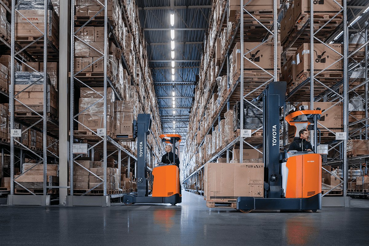 Two Moving Mast Reach Trucks driving through warehouse 