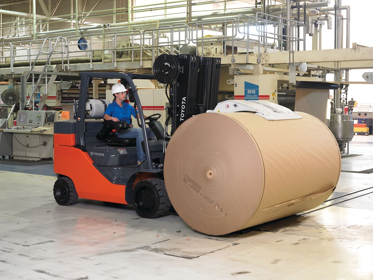 Toyota forklift transporting a large roll of paper in the warehouse