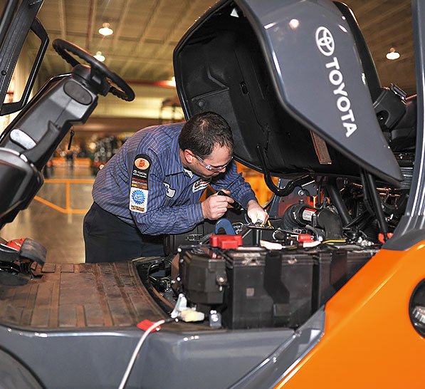 Técnico masculino trabajando en el motor de la carretilla elevadora en el almacén.