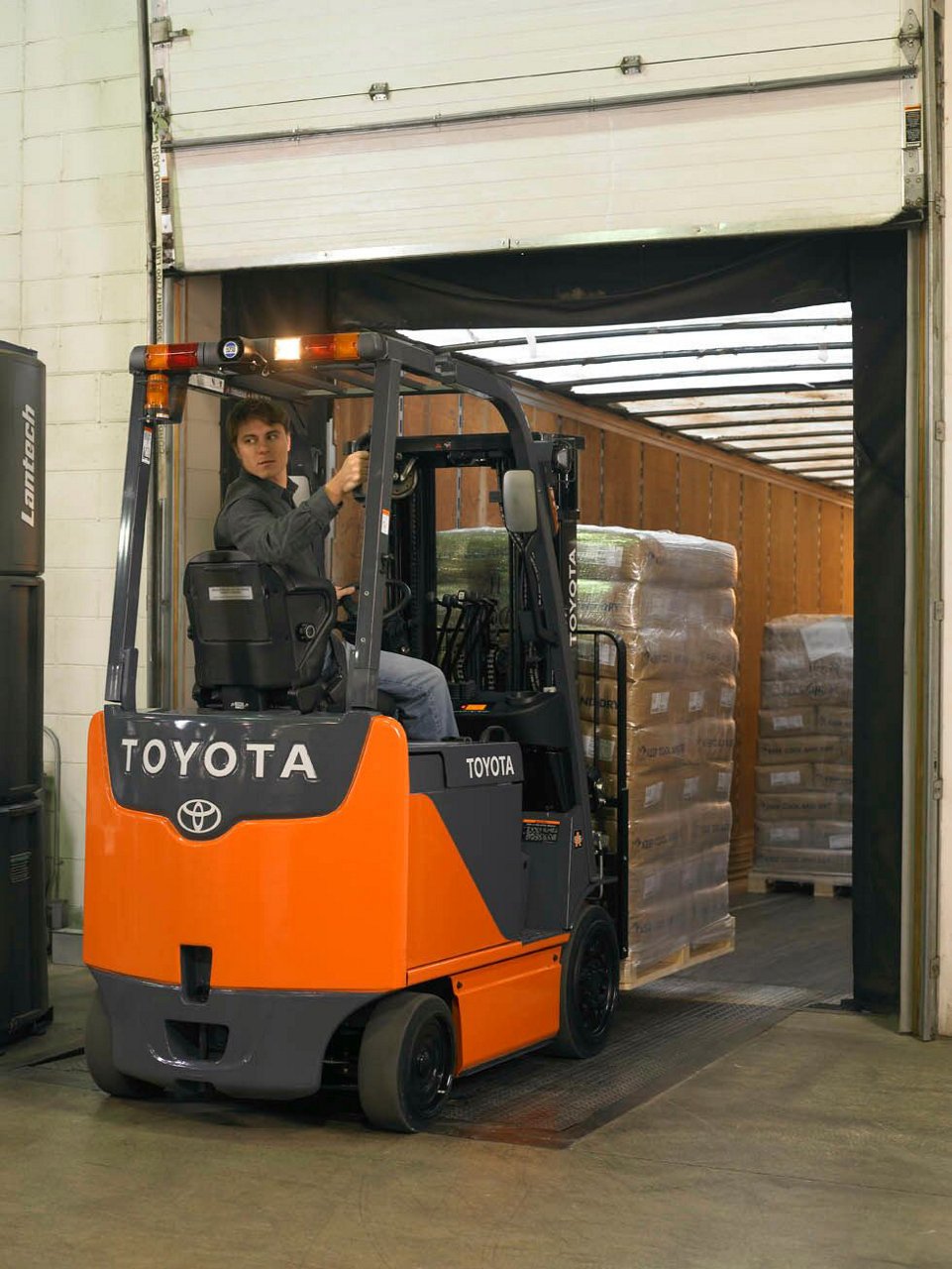  Core Electric Forklift carrying tall stack of materials and reversing in warehouse