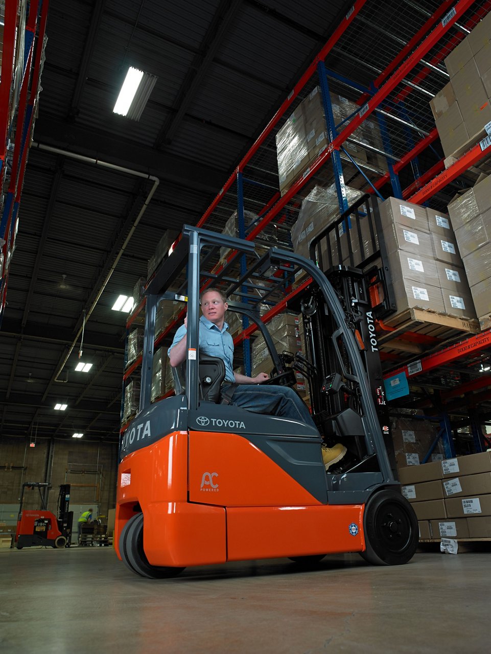 Man driving Toyota 3-Wheel Electric forklift in warehouse 