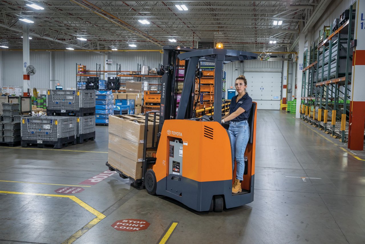 Woman driving Toyota Stand Up Rider in warehouse 