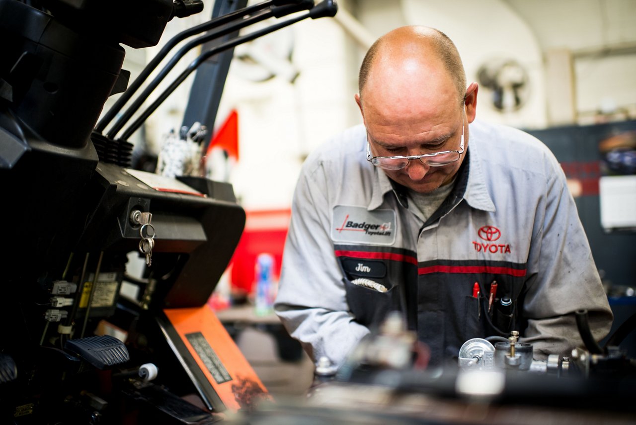 Técnico masculino de Toyota trabajando en el motor de la carretilla elevadora en el almacén