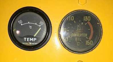 A close up of a circular traditional temperature dial and a similar converter oil dial 