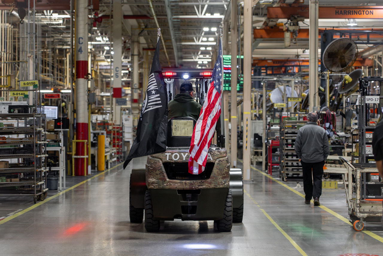 Un chariot élévateur militaire Toyota traverse une usine avec un drapeau américain