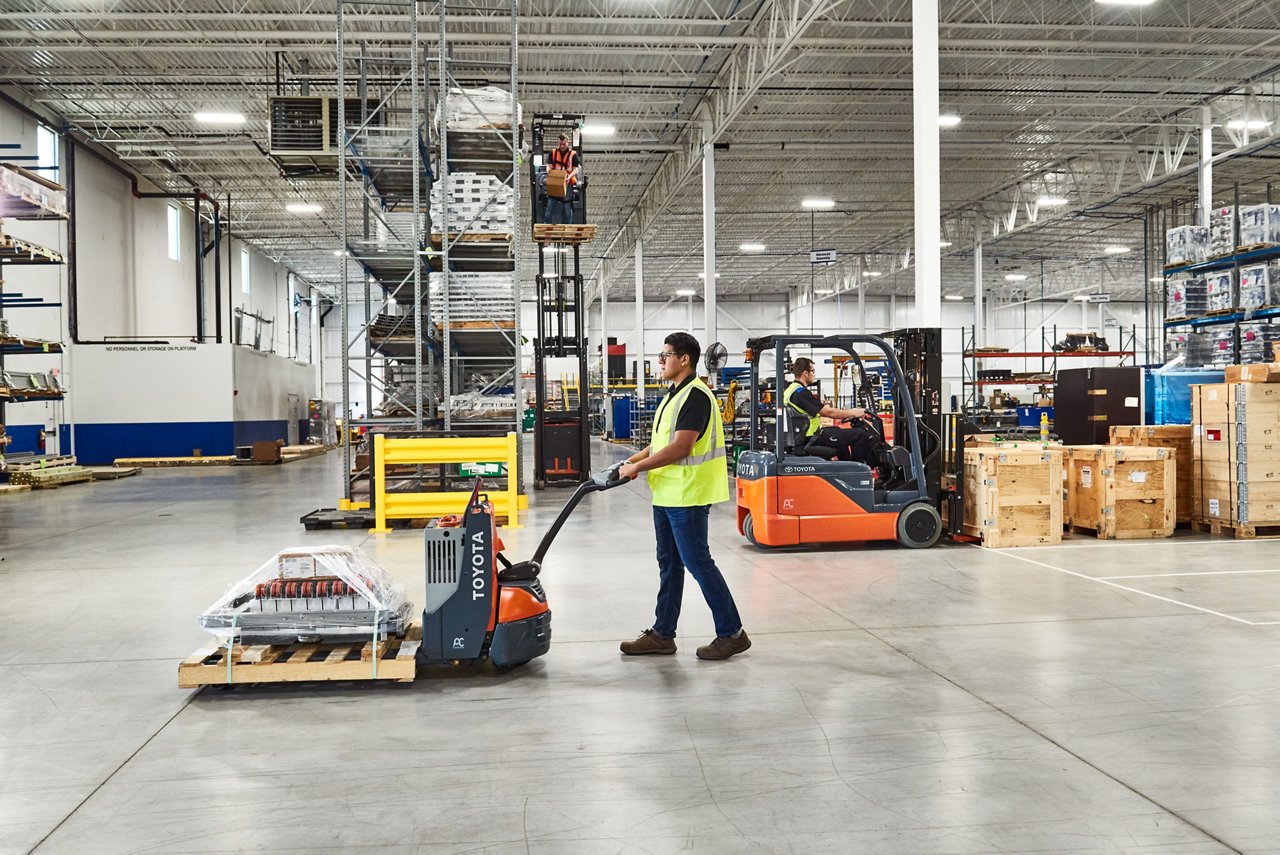 Man uses a Toyota Pallet Jack to carry materials across a warehouse 