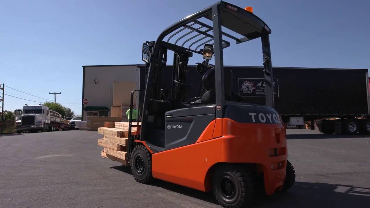 Toyota forklift transporting wooden planks through a wooden lot 