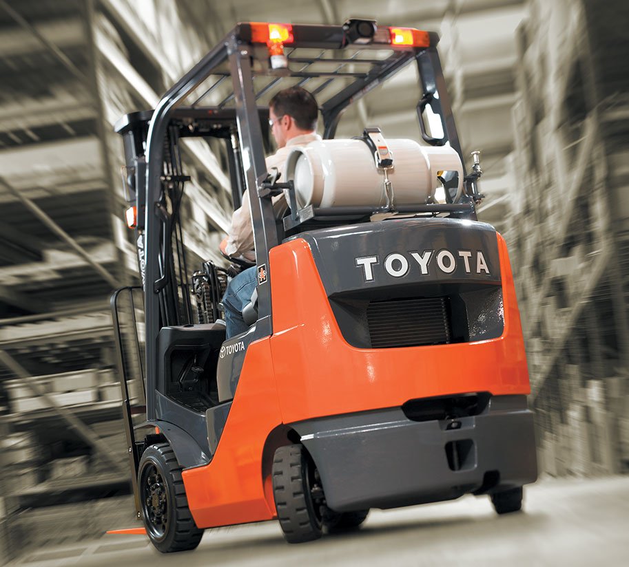 Man driving a Toyota Core IC Cushion forklift in a warehouse