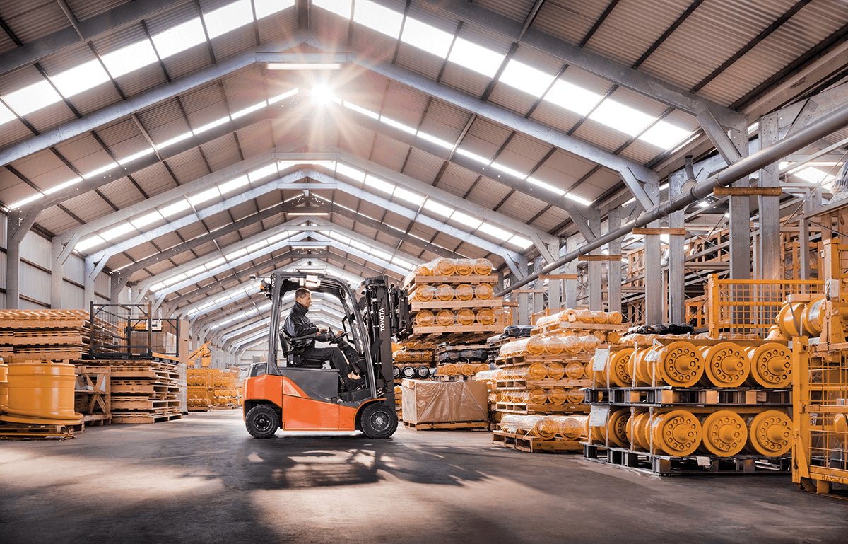 A Toyota Electric forklift carrying 3 stacks of material in a warehouse 