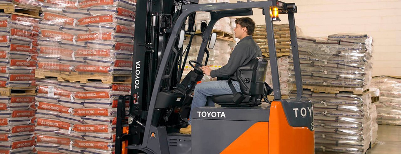 Un hombre utiliza una carretilla elevadora Toyota para recoger muchas bolsas de material en el almacén 