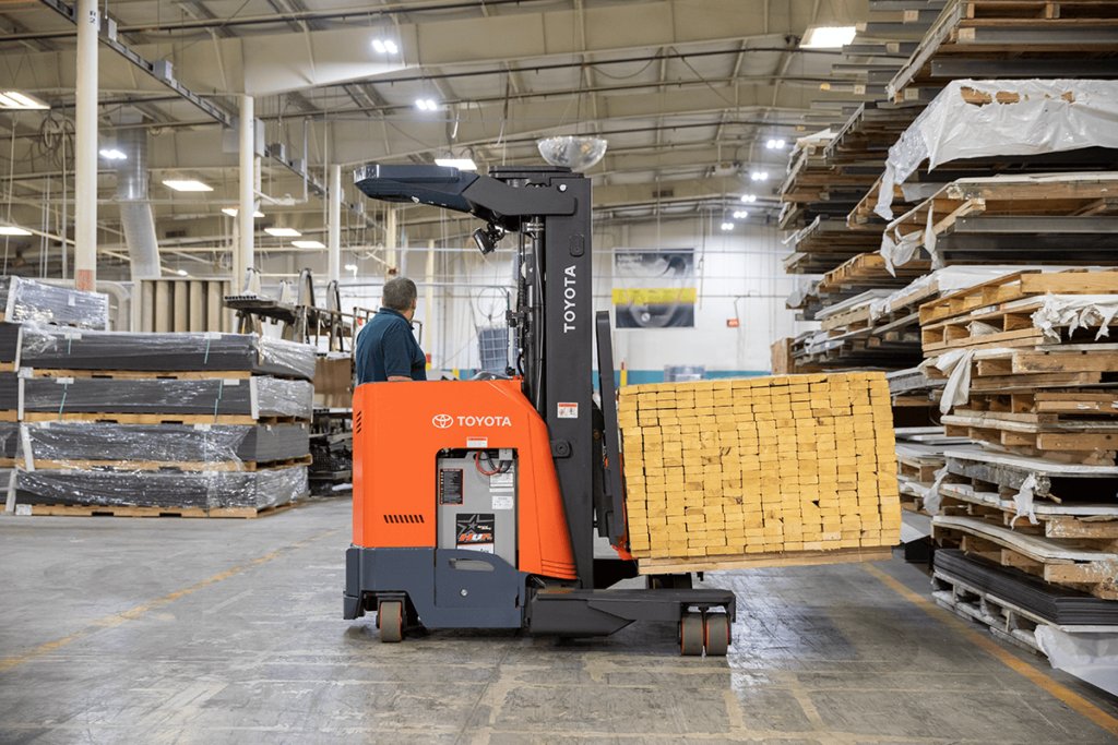 Toyota Reach Truck lifting pallet of many wooden planks in warehouse