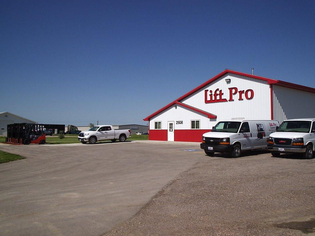 Grey and red image of a building with white technician vans in front