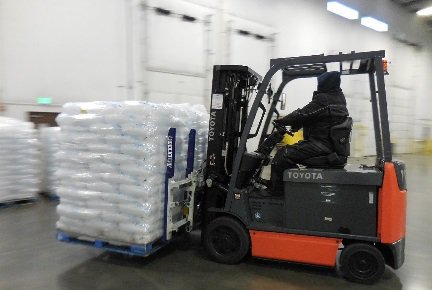 Una carretilla elevadora Toyota transportando un palé con muchas bolsas de hielo en un almacén