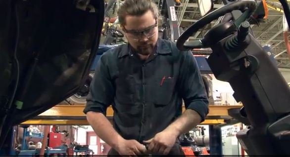 Técnico masculino que trabaja en la carretilla elevadora Toyota en el almacén