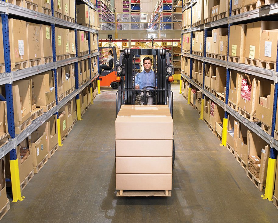 Man driving a Toyota small cushion ic forklift in between two warehouse aisles