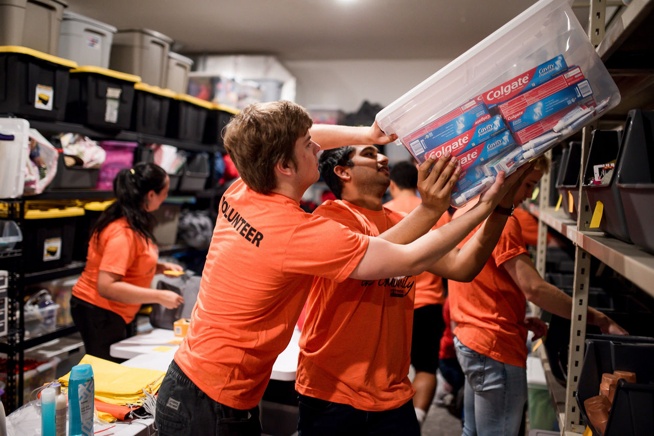 two men wearing toyota volunteer shits lifting box filled with toothpaste