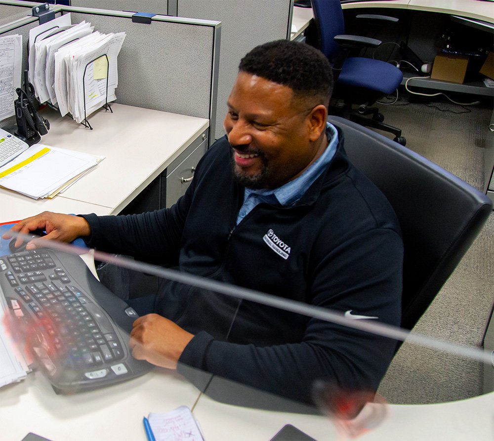 male toyota employee smiling while working on computer