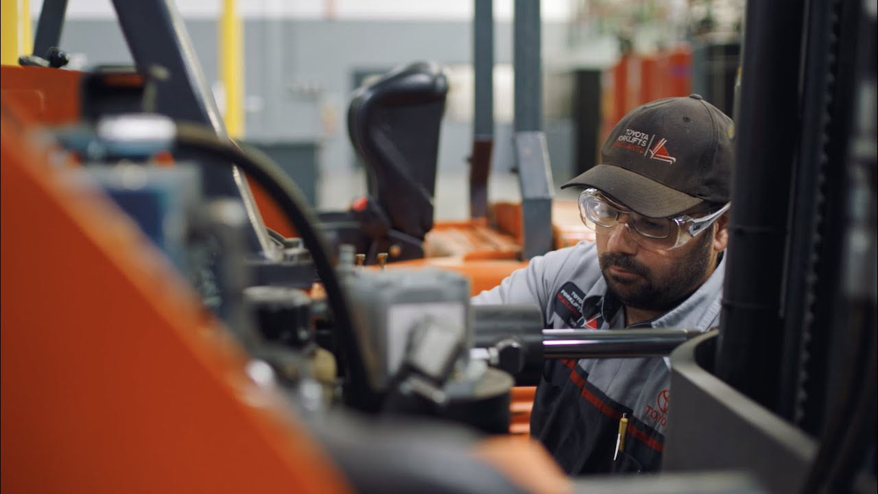 Técnico masculino que trabaja en la carretilla elevadora Toyota en el almacén