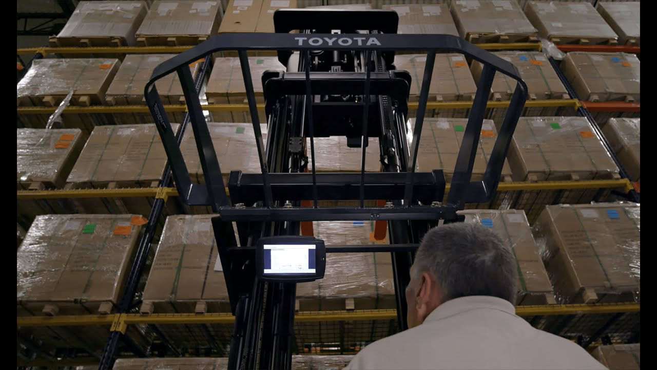 Male technician operating a Toyota reach truck in a warehouse 